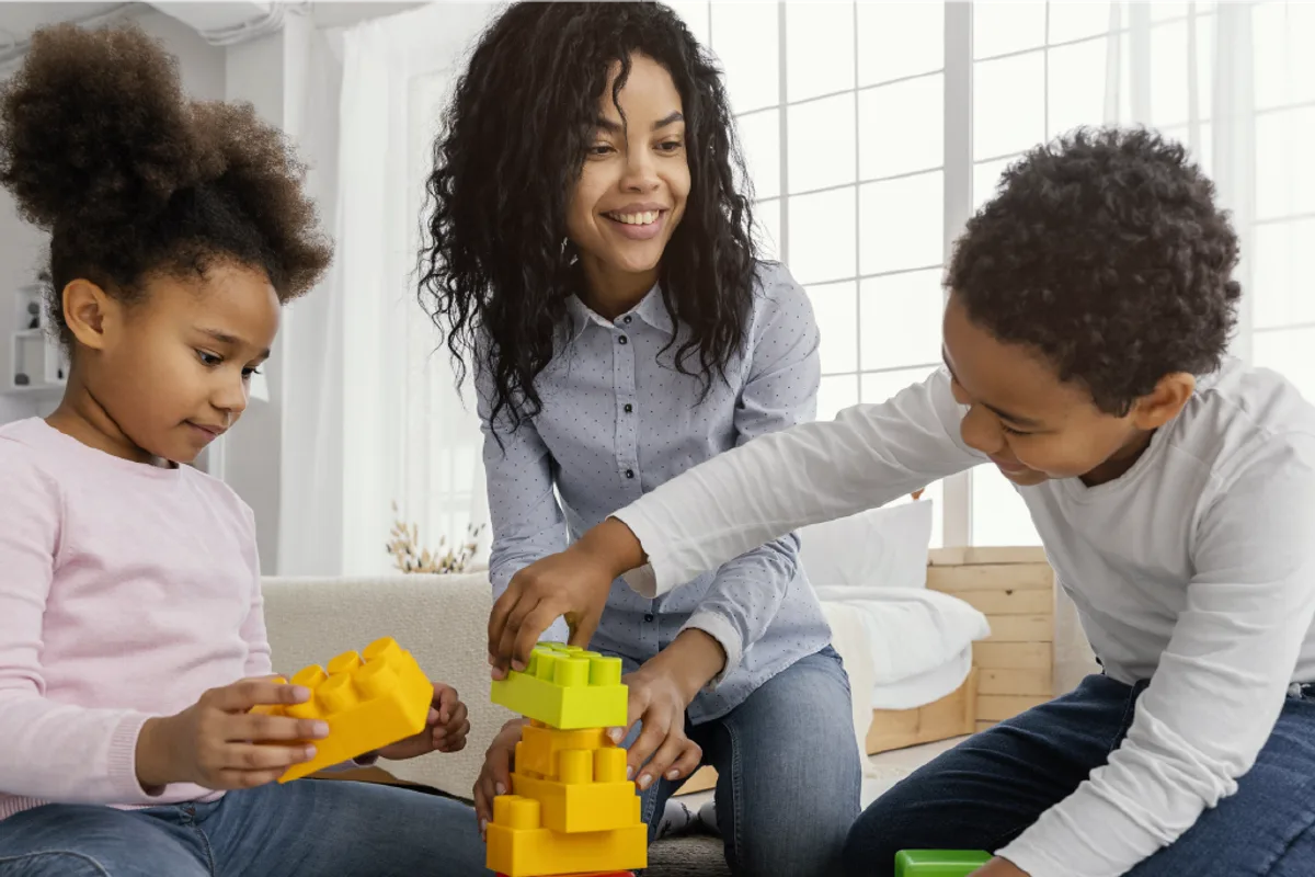 An adult and two children building a tower of colourful blocks at home